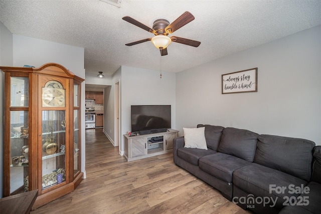 living room featuring light wood-type flooring, a textured ceiling, and ceiling fan