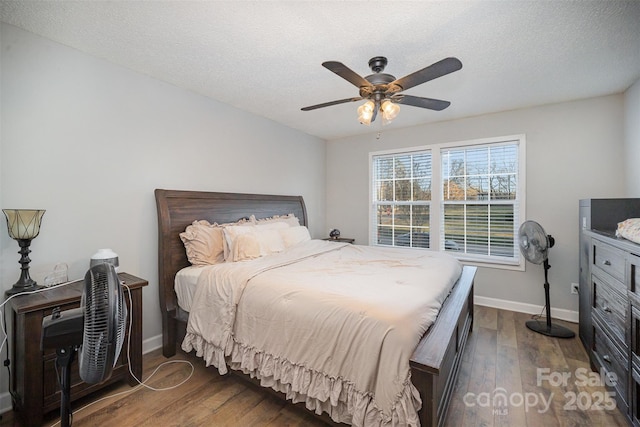 bedroom with ceiling fan, dark hardwood / wood-style floors, and a textured ceiling