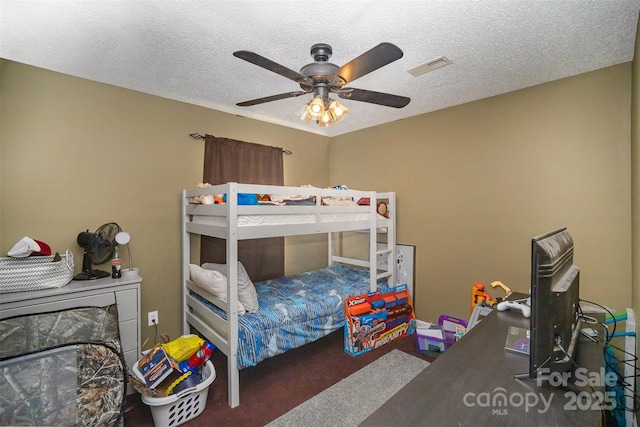 carpeted bedroom with ceiling fan and a textured ceiling