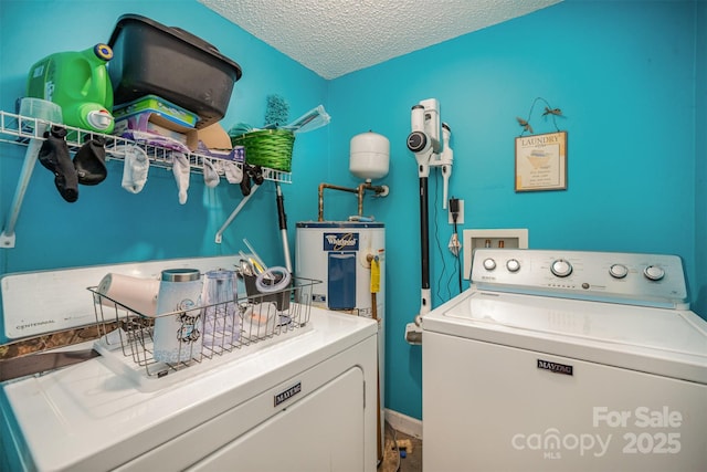 washroom with washing machine and clothes dryer, water heater, and a textured ceiling