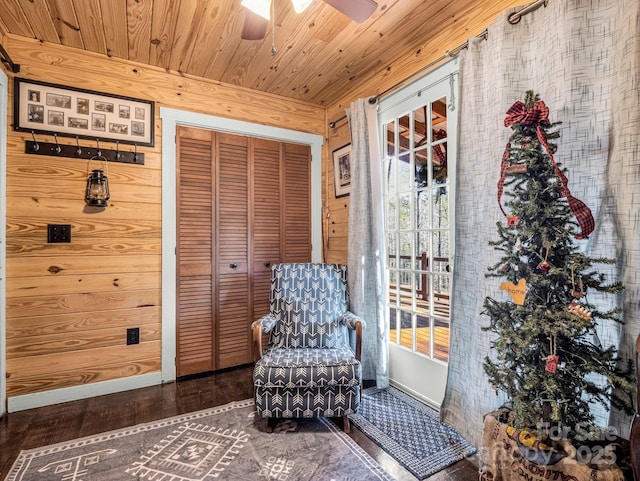 living area featuring ceiling fan, wood ceiling, dark wood-type flooring, and wood walls