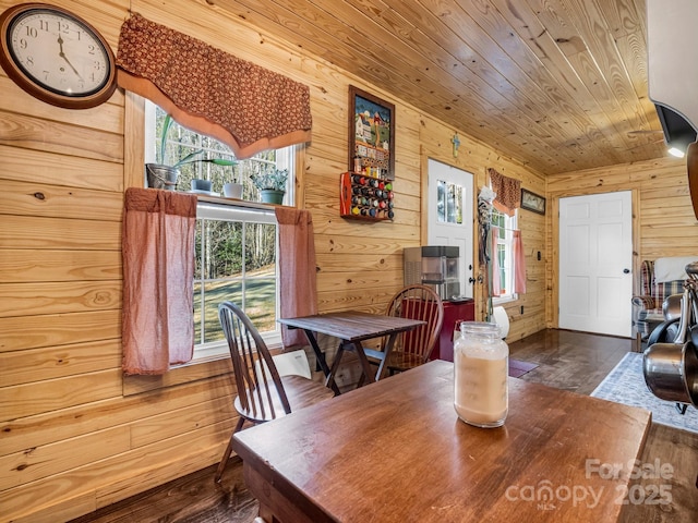 dining space with dark hardwood / wood-style floors, wooden ceiling, and wood walls