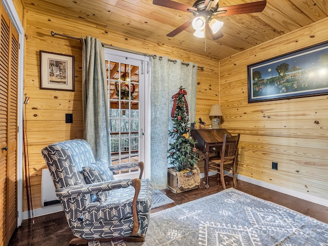 sitting room with wood walls, dark wood-type flooring, ceiling fan, and wood ceiling