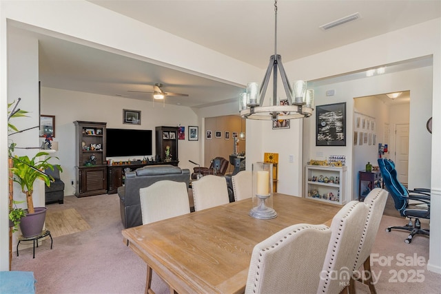 dining room with light carpet and ceiling fan with notable chandelier