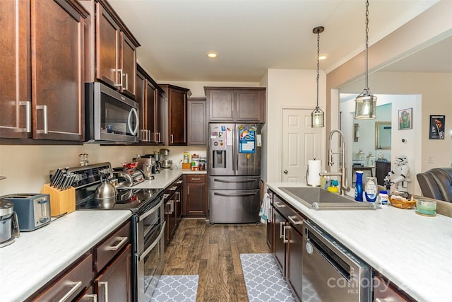 kitchen featuring appliances with stainless steel finishes, dark hardwood / wood-style flooring, dark brown cabinets, sink, and hanging light fixtures