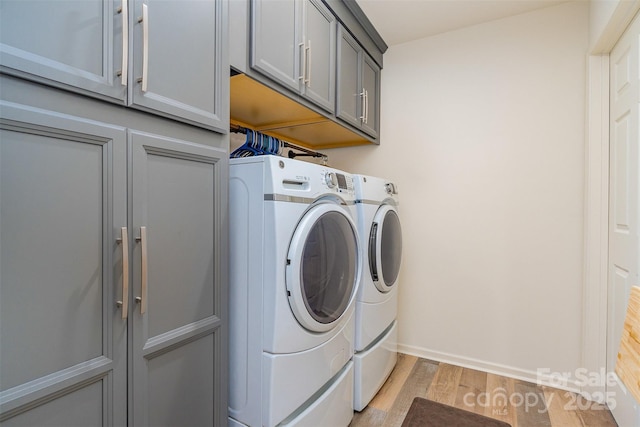 laundry area featuring cabinets, light hardwood / wood-style floors, and washing machine and dryer