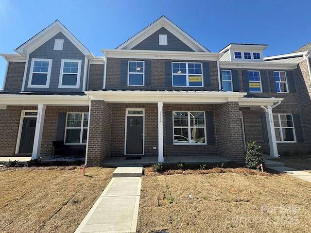 view of front facade featuring covered porch, brick siding, and a front lawn