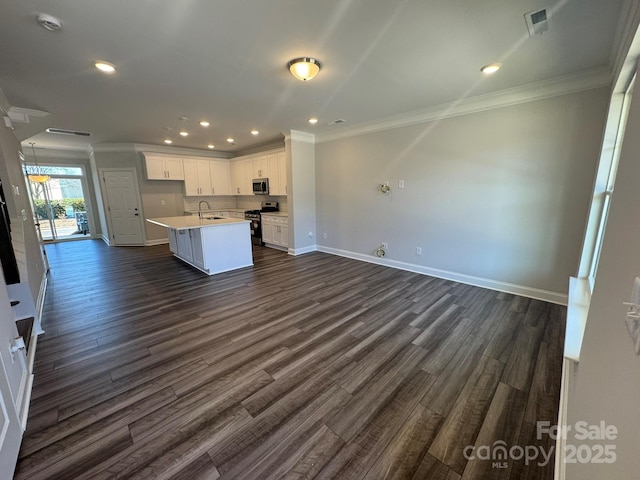 kitchen with stainless steel appliances, open floor plan, a kitchen island with sink, white cabinetry, and a sink