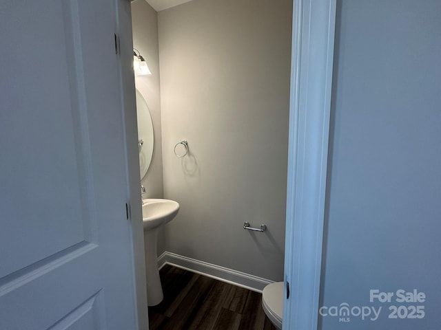 half bath with wood finished floors, toilet, and baseboards