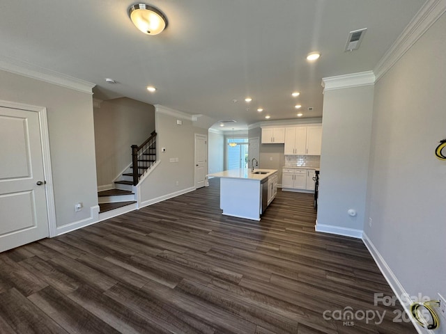 kitchen featuring visible vents, white cabinets, an island with sink, open floor plan, and light countertops