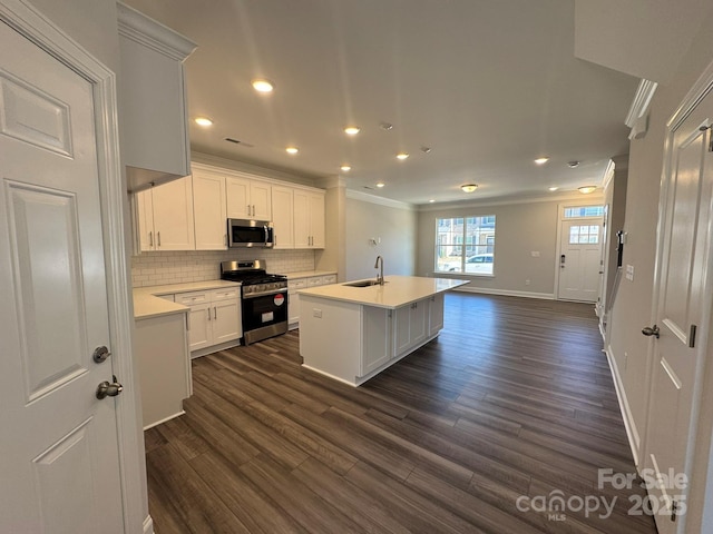 kitchen with stainless steel appliances, light countertops, white cabinetry, a sink, and an island with sink