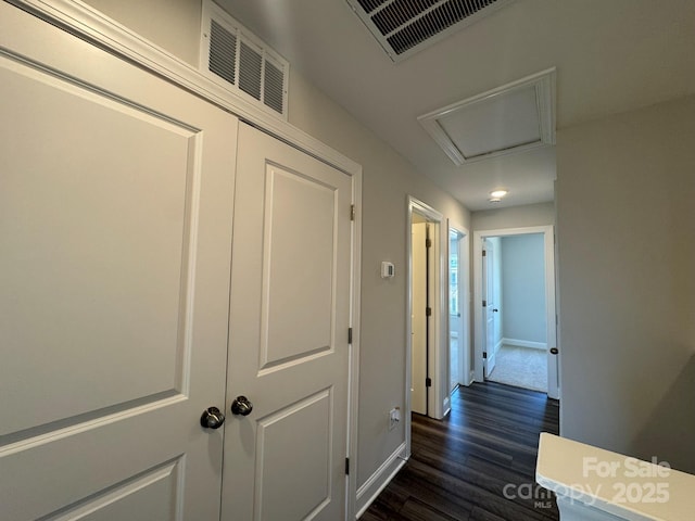 corridor featuring dark wood-type flooring, attic access, visible vents, and baseboards