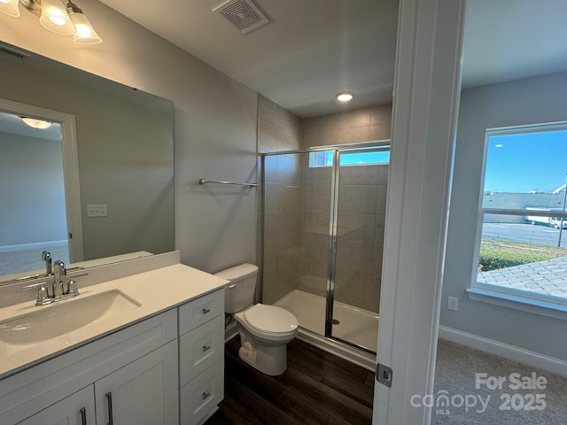 bathroom featuring visible vents, a shower stall, toilet, and vanity