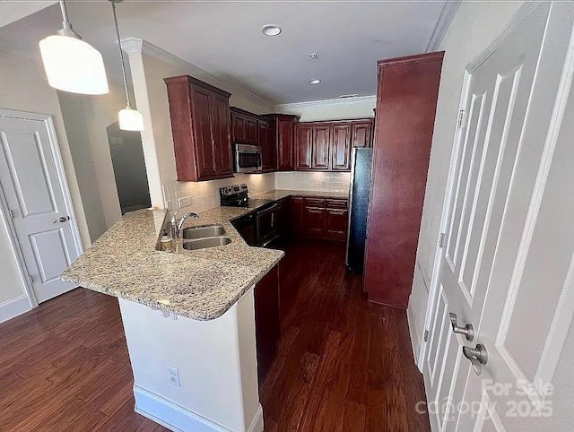 kitchen featuring kitchen peninsula, appliances with stainless steel finishes, a kitchen bar, sink, and decorative light fixtures