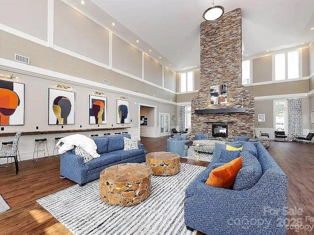 living room featuring hardwood / wood-style flooring, a towering ceiling, and a fireplace