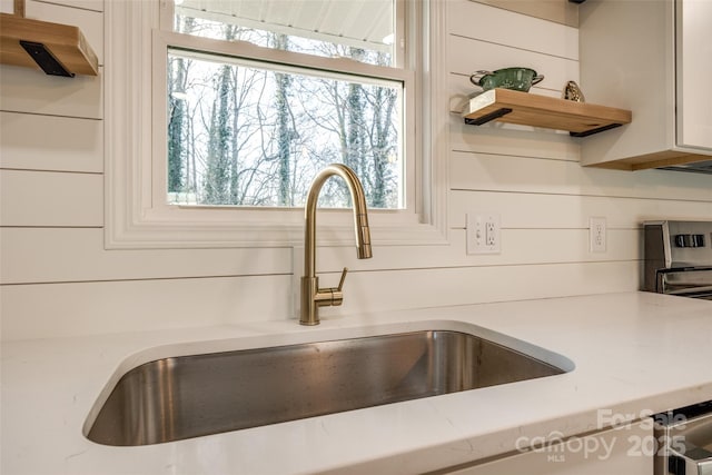 room details featuring wood walls, white cabinetry, and sink