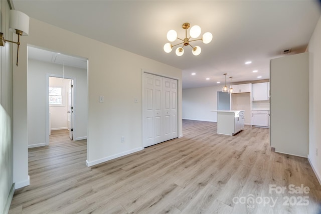 unfurnished living room with an inviting chandelier and light wood-type flooring