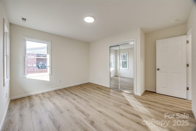 unfurnished bedroom with a closet and light wood-type flooring