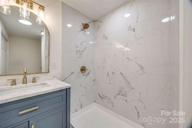 bathroom with tiled shower and vanity