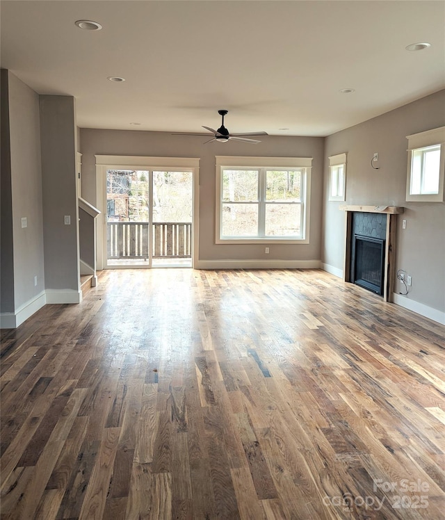 unfurnished living room featuring ceiling fan, baseboards, wood finished floors, and a fireplace