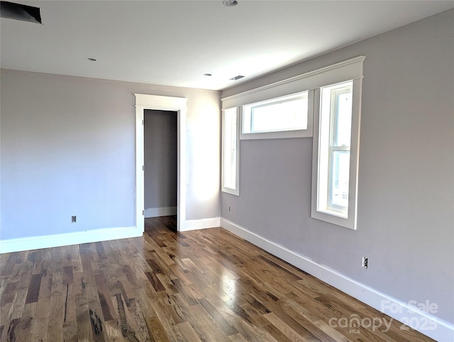 empty room featuring visible vents, baseboards, and wood finished floors