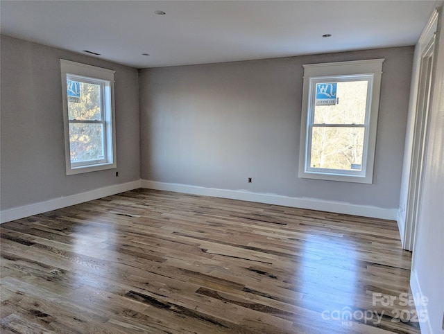 spare room featuring baseboards and wood finished floors