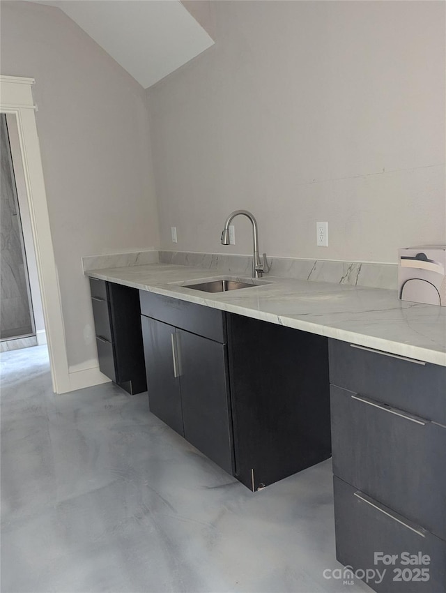 kitchen featuring dark cabinetry, vaulted ceiling, modern cabinets, and a sink