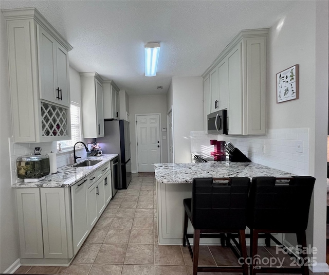 kitchen featuring stainless steel appliances, decorative backsplash, sink, and light stone countertops