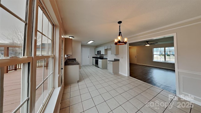 kitchen featuring ceiling fan with notable chandelier, sink, light tile patterned floors, decorative light fixtures, and white cabinetry