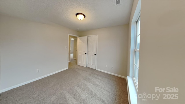 carpeted empty room with a textured ceiling