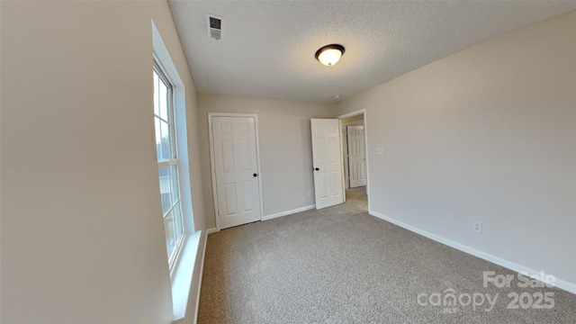 unfurnished bedroom featuring a textured ceiling and light colored carpet