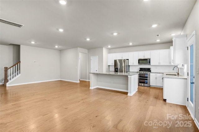 kitchen featuring sink, a center island, light hardwood / wood-style floors, white cabinets, and appliances with stainless steel finishes