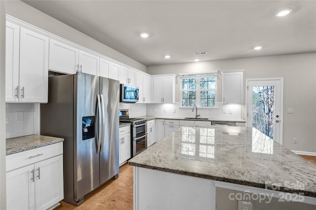 kitchen with white cabinetry, sink, a kitchen island, and stainless steel appliances