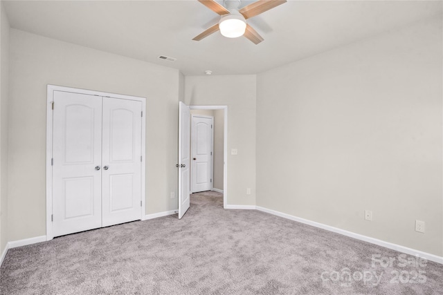 unfurnished bedroom with a closet, light colored carpet, and ceiling fan