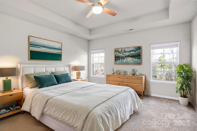 carpeted bedroom featuring a tray ceiling and ceiling fan