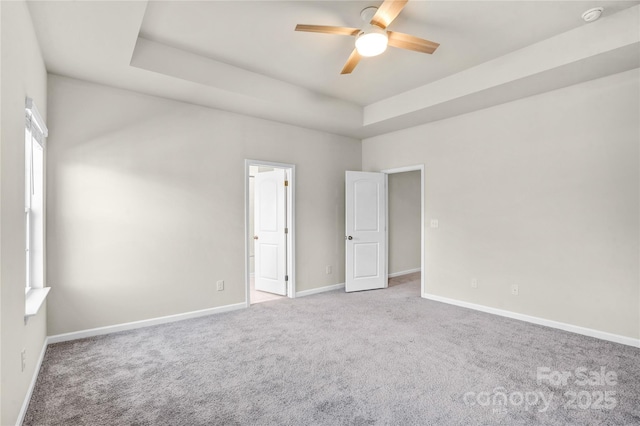 unfurnished room with carpet, ceiling fan, and a raised ceiling