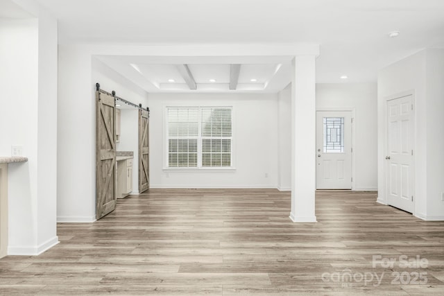 unfurnished living room featuring a barn door and light wood-type flooring