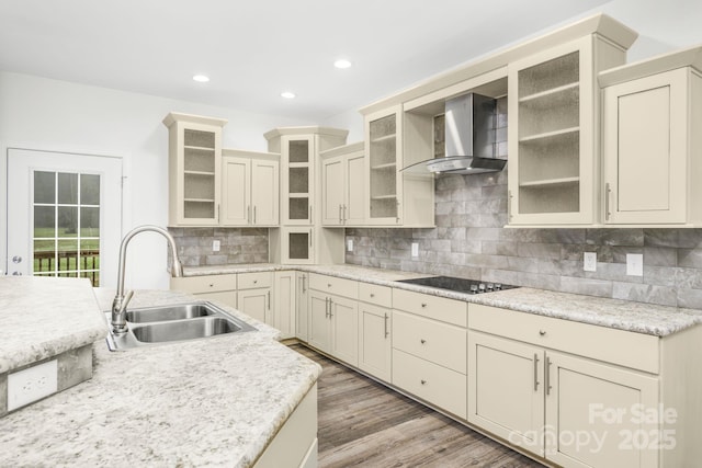 kitchen with sink, wall chimney exhaust hood, backsplash, cream cabinets, and black electric stovetop