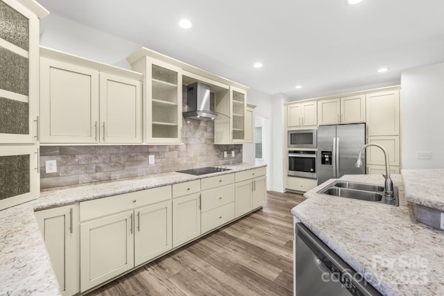 kitchen featuring cream cabinets, sink, stainless steel appliances, and wall chimney range hood