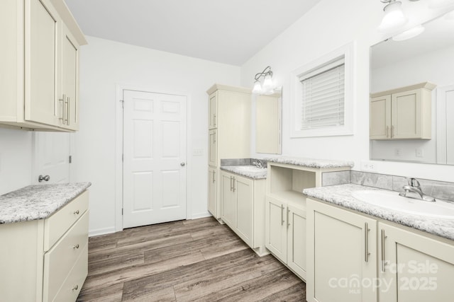 kitchen featuring light stone countertops, cream cabinets, light hardwood / wood-style floors, and sink