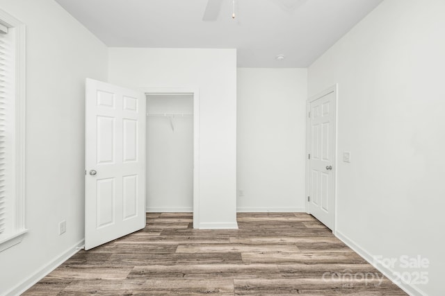 unfurnished bedroom with hardwood / wood-style floors, ceiling fan, and a closet