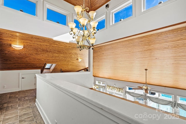 details featuring ceiling fan with notable chandelier, a skylight, and wooden ceiling