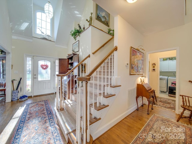 entryway featuring ornamental molding, a healthy amount of sunlight, a high ceiling, and wood-type flooring