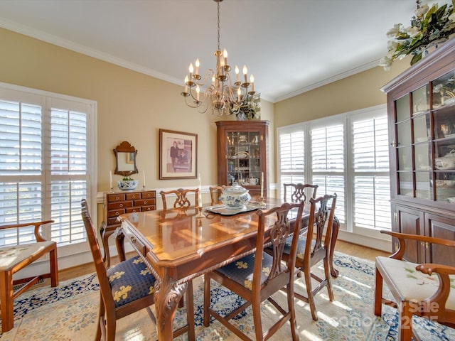 dining area featuring a notable chandelier, light hardwood / wood-style floors, and ornamental molding