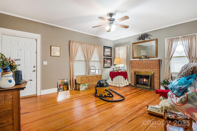 interior space with hardwood / wood-style flooring, ceiling fan, ornamental molding, and a brick fireplace