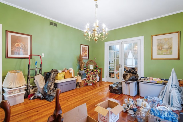 dining room with ornamental molding, wood-type flooring, french doors, and a notable chandelier