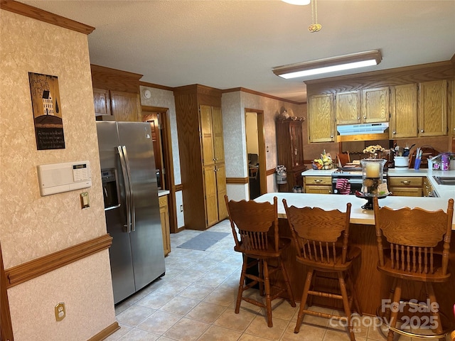 kitchen featuring kitchen peninsula, ornamental molding, appliances with stainless steel finishes, light tile patterned flooring, and a kitchen breakfast bar