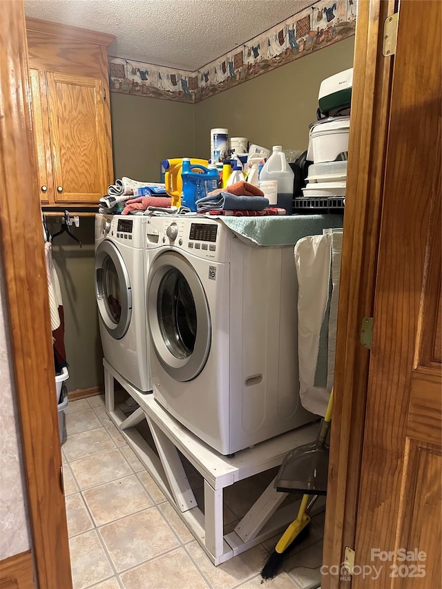 clothes washing area with a textured ceiling, light tile patterned floors, cabinets, and washing machine and clothes dryer