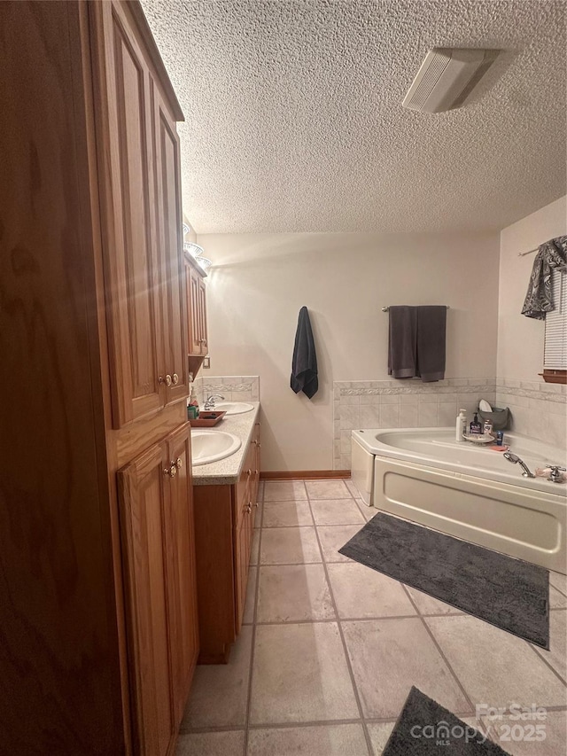 bathroom with a bath, tile patterned flooring, a textured ceiling, and vanity