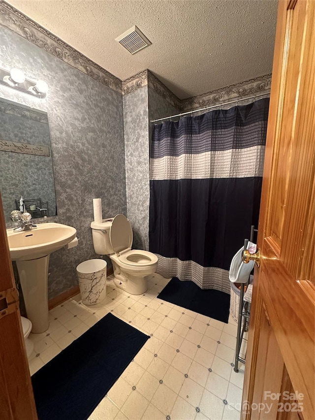 bathroom with toilet, a shower with shower curtain, and a textured ceiling